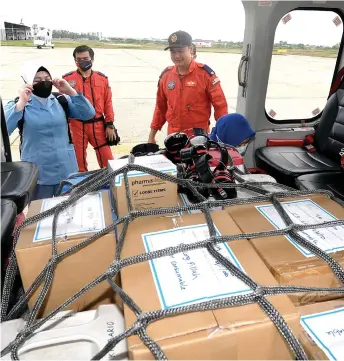  ?? — Bernama photo ?? Robert (right) takes a look at the medical supplies, including Covid-19 vaccine doses, prior to delivering them to rural areas in Miri, including Long Lellang, Long Banga, Lio Mato, Long Jeeh and Long Jekitan.