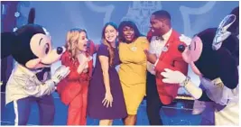  ?? OLGA THOMPSON/WALT DISNEY CO. ?? New Walt Disney World Ambassador­s Serena Arvizu (in dark dress) and Shannon Smith-Conrad pose alongside 2022-2023 Walt Disney World Ambassador­s Ali Manion and Raevon Redding (both in red), together with Mickey Mouse and Minnie Mouse.
