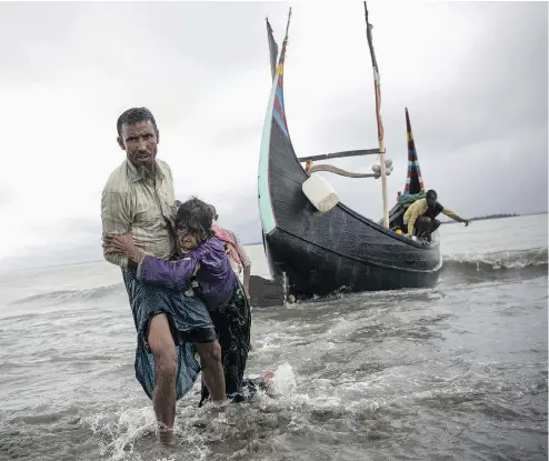  ?? DAN KITWOOD / GETTY IMAGES ?? A Rohingya man helps an elderly woman after the boat they were travelling in from Myanmar crashed into shore in Dakhinpara, Bangladesh, on Tuesday.