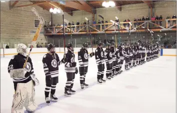  ?? Christian Abraham / Hearst Connecticu­t Media ?? Brunswick hockey team players hold up their hockey sticks during a moment of silence before a game against Millbrook at Hartong Rink in Greenwich on Wednesday. The moment of silence was held in memory of St. Luke’s Teddy Balkind, who died last Thursday at the rink in a junior varsity game against Brunswick.