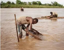  ??  ?? SAKARAHA, Madagascar: Malagasy workers from an informal Sapphire mine seep soil through a strainer in the waters of a river looking for gems.