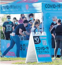  ?? STOCKER/SOUTH FLORIDA SUN SENTINEL MIKE ?? As the omicron variant continues to spread, people line up and wait for COVID-19 tests at the Test Tent facility set up in Hollywood on Thursday. Starting next week, visitors to Broward County buildings, including the libraries, must wear a facial mask to come inside.