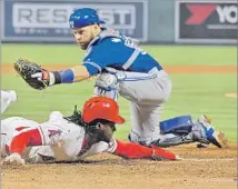  ?? Mark J. Terrill Associated Press ?? THE ANGELS encourage players to slide feet first, but Cameron Maybin, beating a tag by Toronto’s Russell Martin to score in April, still favors the headfirst style, despite an injury last year.