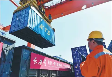  ?? TANG ZHENJIANG / XINHUA ?? A worker watches as cargo is unloaded from a Chang’an freight train in Xi’an, Shaanxi province.