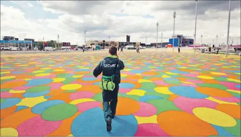  ?? — Photo by The Associated Press ?? A security guard speaks on a mobile phone as he walks near the Olympic stadium at the Olympic Park in London Thursday.