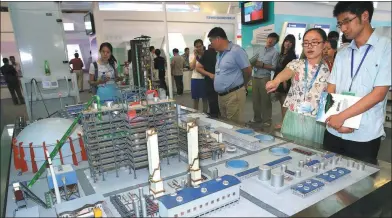  ?? CHEN XIAOGEN / FOR CHINA DAILY ?? Visitors look at a model of an environmen­tal protection project of Shenwu Technology Group Corp at an internatio­nal energy-saving and environmen­tal protection expo in Beijing.