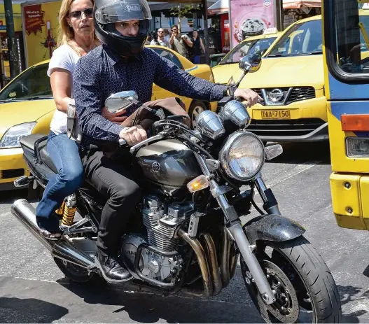  ??  ?? I’m off! Yanis Varoufakis rides away from Greece’s finance ministry after his resignatio­n, with his wife Danae on the back