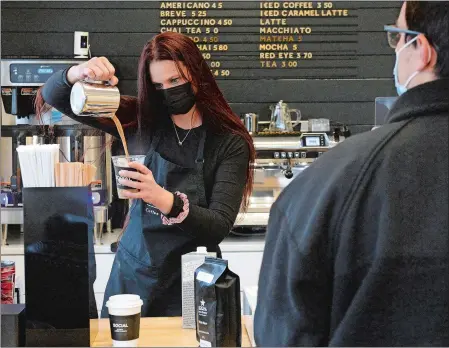  ?? DANA JENSEN/THE DAY ?? Manager Tiffany Irvin pours an iced caramel latte with oat milk Tuesday for customer Colby Womack, right, at the new Social Cafe and Coffee Roastery, owned by Tom Piacenza, in Groton. Piacenza owns two other cafes in Mystic and Stonington.