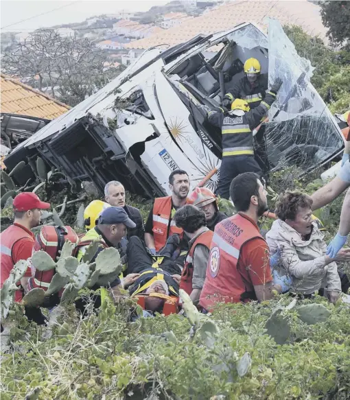  ??  ?? Firemen help victims of the crash after a tourist bus came off the road on the Portuguese island of Madeira