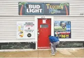  ?? ED ZURGA / GETTY IMAGES ?? A local journalist looks at what appears to be a bullet hole in the door at Tequila KC Bar in Kansas City where four people were shot to death early Sunday.