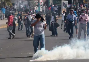  ?? (Oswaldo Rivas/Reuters) ?? A DEMONSTRAT­OR REACTS to a tear gas canister in Managua, Nicaragua, on Friday.