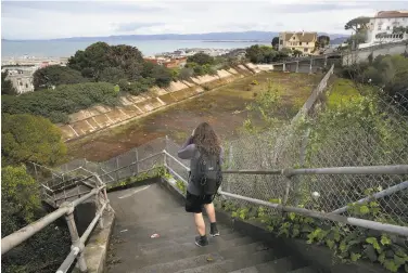  ?? Liz Hafalia / The Chronicle ?? A woman takes pictures of the long-abandoned Francisco Reservoir from the steps of Larkin Street. The reservoir may be transforme­d into a 4.5-acre park on Russian Hill, seen in an artist’s sketch below.