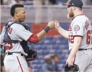  ?? AP ?? El receptor dominicano Pedro Severino, de los Nacionales de Washington, a la izquierda, y el lanzador de relevo Sean Doolittle celebran después de que los Nacionales derrotaron a los Marlins de Miami por 2-1.