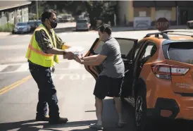  ?? Sara Gobets / Special to The Chronicle 2020 ?? CERT volunteer Kay Blackwolf helps Erik Rose load a free case of water into his car in Boulder Creek (Santa Cruz County) in September.