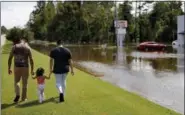  ?? DAVID GOLDMAN — THE ASSOCIATED PRESS ?? A couple walks with their daughter after checking on their flooded home in the aftermath of Hurricane Florence in Spring Lake, N.C., Monday.