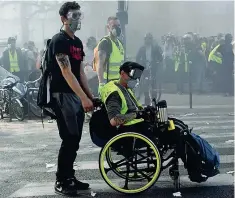  ?? (Getty) ?? In piazza Un manifestan­te dei gilet gialli partecipa alle proteste su una sedia a rotelle; sotto, un altro indossa la maschera di Guy Fawkes del film «V per Vendetta». Nell’immagine grande, i dimostrant­i danno fuoco ad alcune moto. Ieri era il 23esimo sabato di proteste dei gilet gialli, che hanno criticato anche le donazioni dei miliardari francesi per la ricostruzi­one di Notre-dame