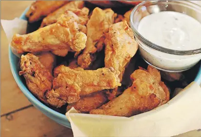  ?? AP PHOTO ?? Even though Superbowl Sunday is still almost two weeks away, it's not too early to start planning the menu. Party wings with cilantro sour cream dip and honey sriracha require almost no effort as the secret lies in the baking powder.