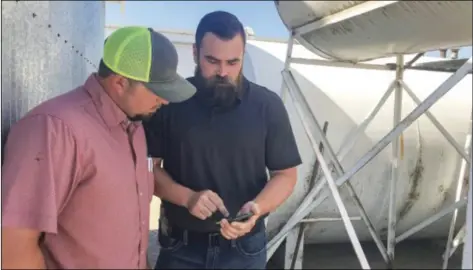  ??  ?? Colusa County sheriff’s sgt. Mike Bradwell (right) shows Grimes farmer Jake Driver a smartphone applicatio­n meant to help facilitate communicat­ion between deputies and residents, and to report anything suspicious happening on the farm. PHOTO CHRISTINE SOUZA, CALIFORNIA FARM BUREAU FEDERATION