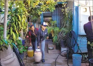  ??  ?? DALIA HELPS her grandmothe­r Elizabeth Meza, with whom she lives, carry aguas before a catering job in February. Dalia often assists her grandmothe­r in selling homemade tacos.