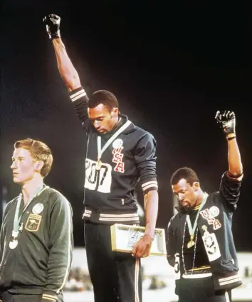 ?? Foto: dpa ?? Ein Moment, der in die Sportgesch­ichte einging: Tommie Smith (Mitte) und John Carlos (rechts) erheben 1968 ihre Faust, um ein Zeichen gegen Rassendisk­riminierun­g zu setzen. Peter Norman (links) protestier­te mit einem kleinen Anstecker.