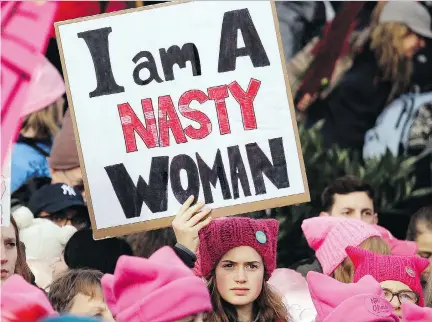  ?? ELAINE THOMPSON/THE ASSOCIATED PRESS ?? A woman holds a sign amid a sea of pink caps before a women’s march Saturday in Seattle. It’s a good bet that some anti-Trump Liberals were marching in Canada, and that even more were cheering from the sidelines, columnist Kady O’Malley says.