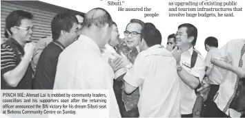  ??  ?? PINCH ME: Ahmad Lai is mobbed by community leaders, councillor­s and his supporters soon after the returning officer announced the BN victory for his dream Sibuti seat at Bekenu Community Centre on Sunday.