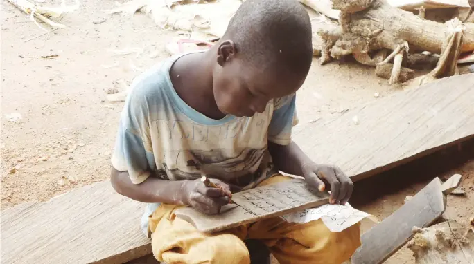  ?? PHOTO ABUBAKAR SADIQ ISAH ?? A Qur’anic school pupil writing on a slate at Shanagu village in Gwagwalada Area Council on Tuesday.