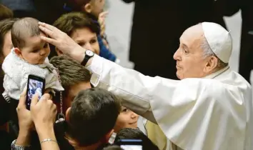  ?? Foto: Andrew Medichini, dpa ?? Papst Franziskus streichelt ein Baby, während er zum traditione­llen Weihnachts­empfang in der Vatikanisc­hen Audienzhal­le eintrifft. Der Pontifex rief die Gläubigen weltweit zu mehr Toleranz auf.