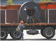  ?? Cole Burston / Getty Images ?? Steel coils are fastened to a truck in preparatio­n for shipping from a steel plant in Hamilton, Canada.