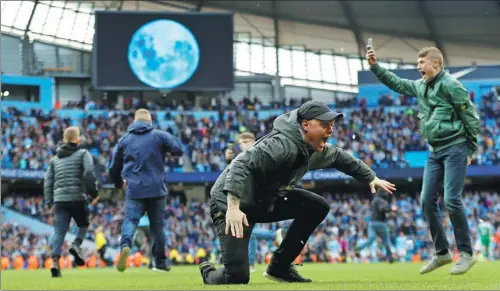  ?? REUTERS ?? Manchester City fans cavort on the pitch after Sunday’s 5-0 English Premier League victory over Swansea at Etihad Stadium.
