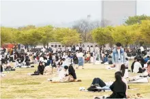  ?? Yonhap ?? Picnickers sit on the grass at Yeouido Hangang Park in southern Seoul, April 10.