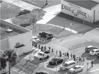  ?? Mike Stocker/South Florida Sun-Sentinel via AP, File ??    In this Feb. 14 file photo, students are evacuated by police from Marjory Stoneman Douglas High School in Parkland, Fla., after a shooter opened fire on the campus. A large Wall Street money manager wants to engage with major weapons manufactur­ers...