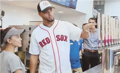  ?? STAFF PHOTOS BY ANGELA ROWLINGS ?? FINDING THAT SWEET SPOT: Dunkin’ employee Luna Lama, above, shows Red Sox player Xander Bogaerts how to work the tap at Dunkin’ on City Hall Plaza. ‘Selfie’ doughnuts are shown below.