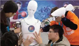  ?? —AP ?? BEIJING: Chinese students work on the Ares, a humanoid bipedal robot designed by them with fundings from a Shanghai investment company, displayed during the World Robot Conference in Beijing.