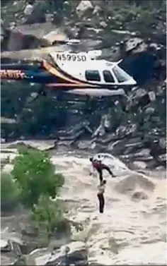  ??  ?? In the nick of time: A stranded hiker is rescued from torrential flash flood waters near Tucson, Arizona. — AP