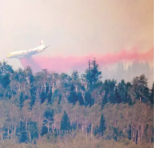  ?? DARRYL DYCK / THE CANADIAN PRESS ?? A tanker drops retardant while battling the Shovel Lake wildfire near Fraser Lake, B.C., on Friday. In addition to fire retardant, crews have lit back burns, where a fire is lit in front of the wildfire with the intent of consuming all the fuel, thereby stopping the out-of-control fire.
