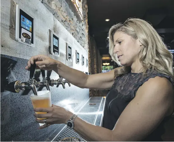  ?? SHAUGHN BUTTS ?? Heather Seale pours herself a Beaver Tail Raspberry Ale from Canmore at Alberta’s first self-serve beer and wine wall in the Leduc location of Barney’s pub. Plastic purchase cards limit patrons to 32 ounces of beer before they expire and need to be...
