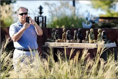  ?? Arkansas Democrat-Gazette/MITCHELL PE MASILUN ?? John Mayner takes a photo of the sculpture Renewal Ritual on Sunday before the start of a news conference announcing the addition of more artwork at the Vogel Schwartz Sculpture Garden in Little Rock.