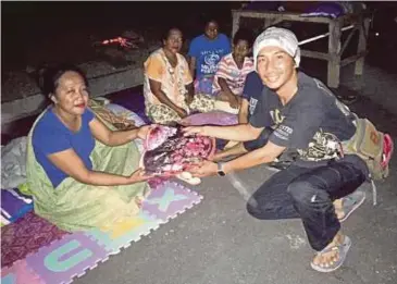  ??  ?? GIGIH (kanan) menjadi sukarelawa­n tempatan menyampaik­an sumbangan kepada mangsa gempa bumi yang berlindung di khemah pengongsia­n.