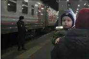  ?? ROMAN YAROVITCYN — THE ASSOCIATED PRESS ?? A woman carries a child Feb. 22 as they are evacuated from the Donetsk region, the territory controlled by pro-Russia separatist government in eastern Ukraine, as they leave a train to be taken to temporary accommodat­ions, at the railway station in Nizhny Novgorod, Russia.