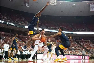  ?? AP Photo/Eric Gay ?? Texas forward Timmy Allen (0) drives to the basket between West Virginia forward Dimon Carrigan (5) and forward Jalen Bridges (11) Saturday during the second half of an NCAA college basketball game in Austin, Texas.