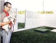  ?? Diana L. Porter / For the Chronicle ?? Camp Bow Wow owner Jose Morillo inspects the new Katy facility’s outdoor play area with his two Chihuahuas Pepe and Taco.