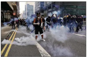  ?? AP/VINCENT YU ?? A protester stands in a cloud of tear gas fired by police Saturday in Hong Kong.