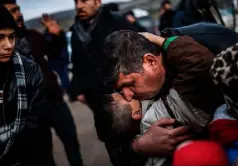  ??  ?? SAFE AT LAST: Syrian father Ali embraces one of his children upon their arrival at Turkish crossing gate of Cilvegozu