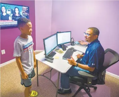  ?? JERRY JACKSON/BALTIMORE SUN ?? Joe White takes a break from remote work in his home office to answer a question from J.J., his 9-year-old son. White, a utility training center manager for BGE, has embraced the benefits of working from home.