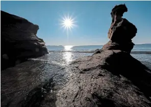  ??  ?? The sun rises beyond a sandstone spire, which the sea has separated from the shore in the Magdalen Islands.