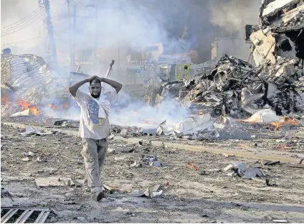  ?? Farah Abdi Warsameh ?? > A man walks through the wreckage at the scene of a blast in the Somali capital Mogadishu on Saturday