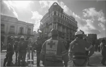  ?? AP PHOTO/ISMAEL FRANCISCO ?? MEMBERS OF THE RED CROSS GATHER near the ruins at the site of a deadly explosion that destroyed the five-star Hotel Saratoga in Old Havana, Cuba, on Sunday.