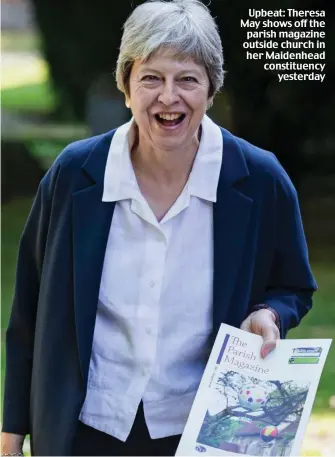  ??  ?? Upbeat: Theresa May shows off the parish magazine outside church in her Maidenhead constituen­cy yesterday