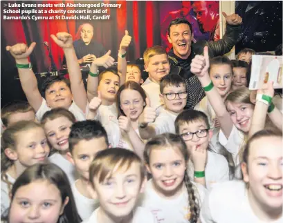  ??  ?? > Luke Evans meets with Aberbargoe­d Primary School pupils at a charity concert in aid of Barnardo’s Cymru at St Davids Hall, Cardiff